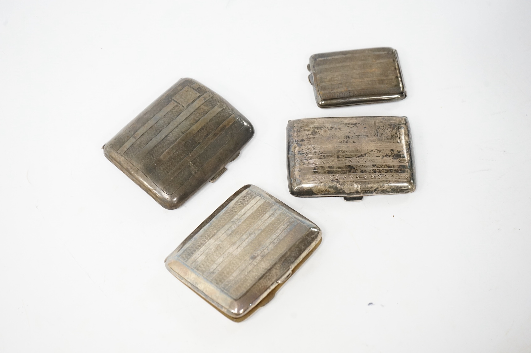 Three assorted George V silver cigarette cases and a silver matchbook case. Condition - fair